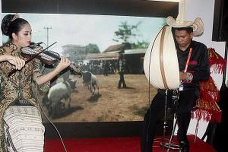 Ivan Pah (kanan) asal Rote Ndao, bersama seorang putri pemain biola asal Jakarta, memainkan alat musik tradisional asal Nusa Tenggara Timur di depan stan produk pariwisata Indonesia di Kuala Lumpur, Malaysia. Pengunjung berjubel menyaksikan alat musik ini, Jumat (4/9/2015).
