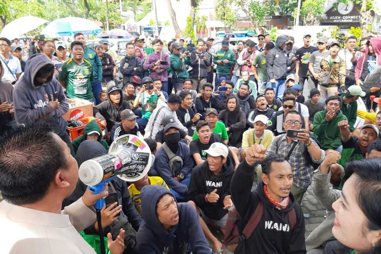 Pendukung Persebaya bernyanyi di depan pintu gerbang Pengadilan Negeri Surabaya usai mendengarkan putusan hakim soal gugatan hak pakai wisma atlet, Selasa (10/3/2020).