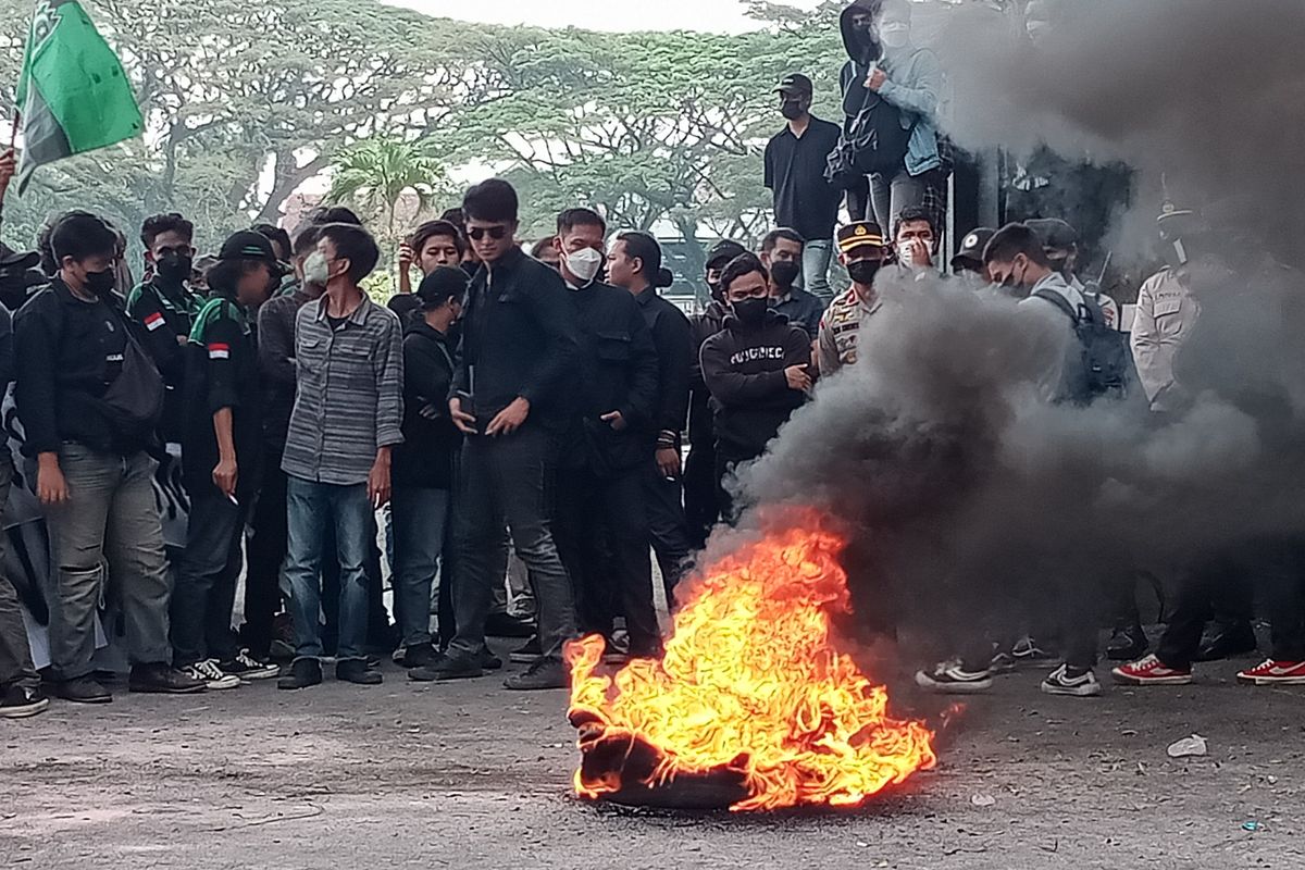 Mahasiswa membakar ban bekas saat melakukan demonstrasi menuntut pencopotan Menteri Perdagangan (Mendag) RI, M Lutfi di depan pintu masuk gedung DPRD Kota Malang pada Selasa (22/3/2022) siang. 