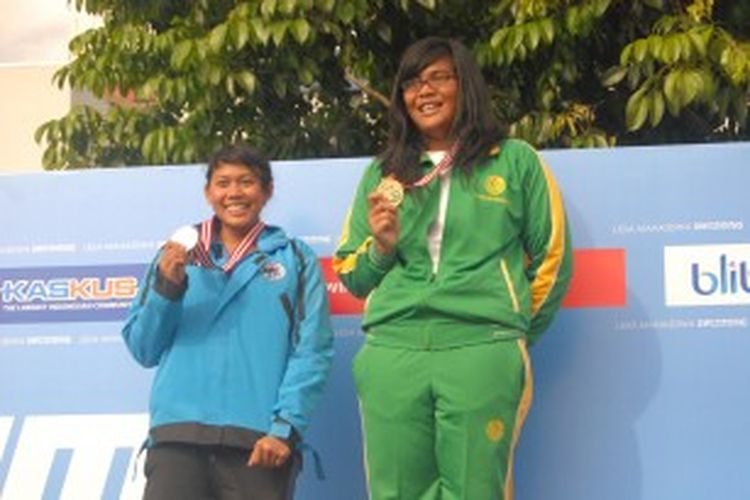 Perenang Universitas Negeri Jakarta (UNJ), Sinar Tri U. Chaniago (kanan) membanggakan medali emas dari nomor 100 meter gaya punggung putri dengan catatan waktu 1 menit 19,67 detik, pada Liga Mahasiswa Swimming 2013, Sabtu (29/6/2013.