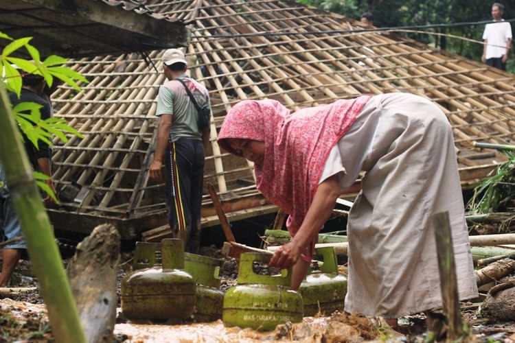 Seorang warga korban tanah longsor di wilayah Kecamatan Cibeber, Kabupaten Cianjur, Jawa Barat, tengah membersihkan barang miliknya pasca tebing setinggi 200 meter longsor dan menerjang rumahnya, Minggu (22/3/2020) dini hari.