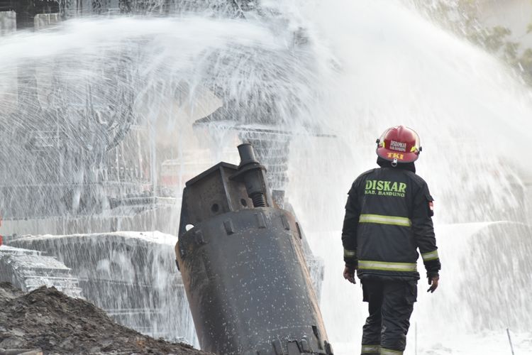 Petugas tengah berupaya memadamkan alat berat kontruksi pada kebakaran pipa minyak pertamina, Selasa (22/10/2019).