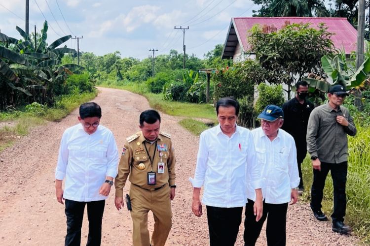 Presiden Joko Widodo bersama Menteri PUPR Basuki Hadimuljono dan Gubernur Jambi Al Haris berjalan kaki saat meninjau kerusakan di ruas jalan Kota Jambi-Sungai Gelam di Provinsi Jambi, pada Selasa (16/5/2023).