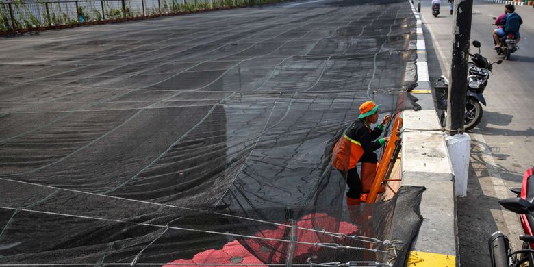 Pekerja memasang jaring-jaring untuk menutupi aliran Kali Sentiong atau Kali Item di Jakarta Utara, Jumat (20/7/2018). Pemasangan jaring-jaring berbahan nilon untuk mengatasi buruknya rupa Kali Item sebelum menerima para atlet Asian Games 2018 dari mancanegara yang akan menginap di Wisma Atlet.