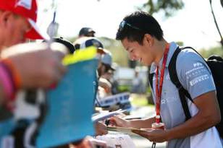 Pebalap Manor Racing asal Indonesia, Rio Haryanto, memberikan tanda tangan kepada para penggemar yang menunggu di Sirkuit Melbourne Grand Prix, Albert Park, Kamis (17/3/2016).