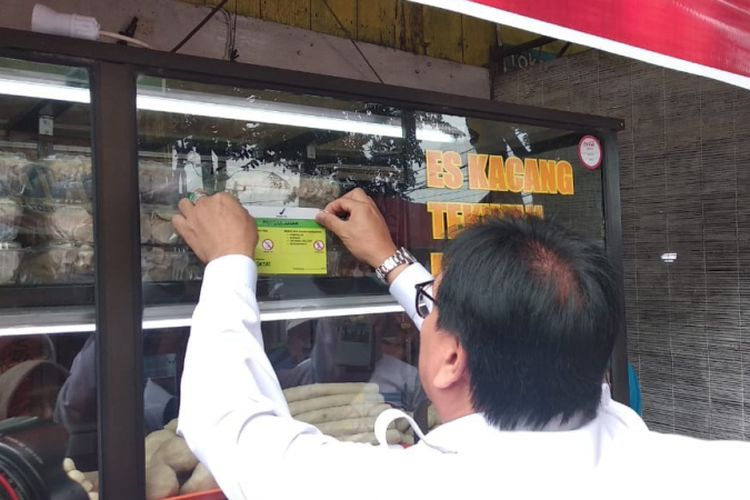 Sekda Provinsi SUmsel Nasrun Umar memasang stiker bebas formalin usai meninjau bersama BPOM Palembang di sentral kampung pempek di jalan Mujahidin , Palembang, Sumatera Selatan, Senin (25/6/2018).
