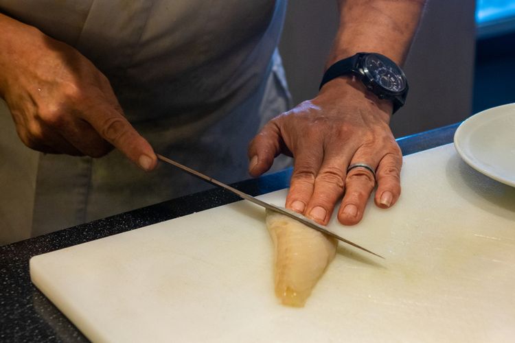 Ilustrasi seorang chef restoran di Singapura terlihat memotong ikan buntal.