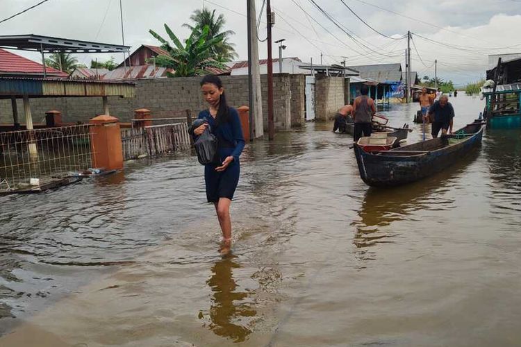 Seorang wanita muda warga Desa Hutadaa membawa barang berharganya meninggalkan rumahnya untuk mengungsi ke tempat yang lebih aman setelah air Danau Limboto meluap. Banyak rumah warga yang terendam hingga ketinggian dada orang dewasa.