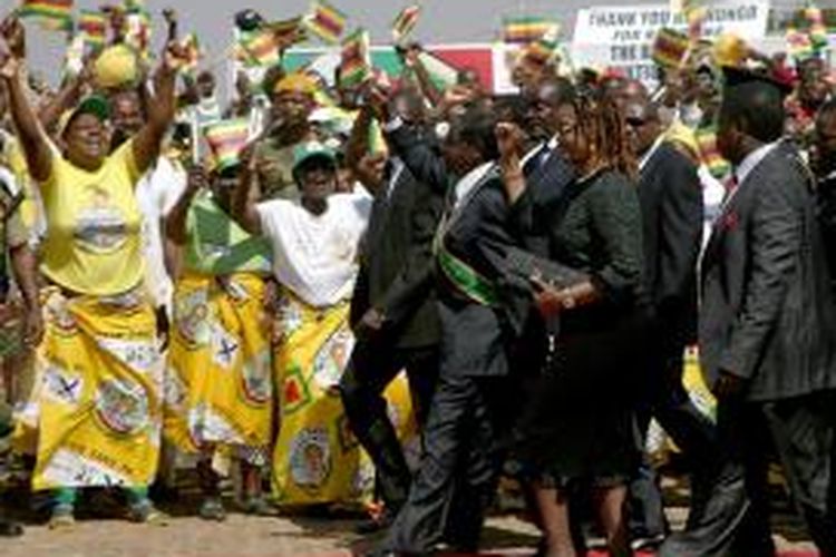 Presiden Robert Mugabe melambaikan tangan pada pendukungnya saat tiba dalam upacara Hari Pahlawan Zimbabwe, Senin (12/8/2013).