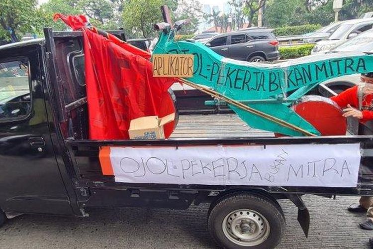 Kelompok pengemudi ojek online atau ojol bernama Serikat Pekerja Angkutan Indonesia (SPAI) membawa motor dari bahan kardus saat ikut unjuk rasa Omnibus Law di depan Gedung DPR RI, Senayan, Jakarta Pusat pada Rabu (10/8/2022).
