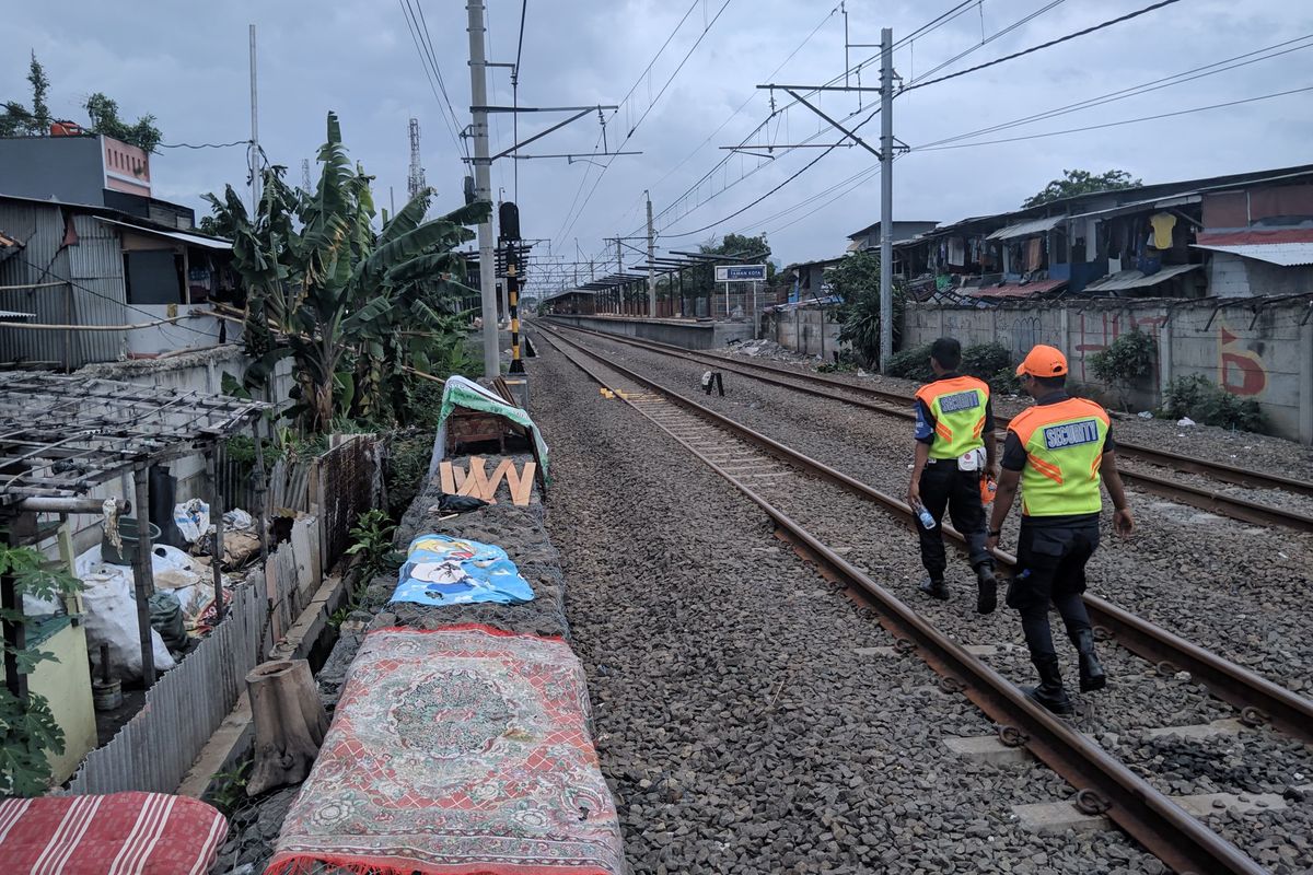 Dua petugas keamanan mengecek jalur kereta di sekitar Stasiun Taman Kota Jakarta Barat, Minggu (5/1/2020)