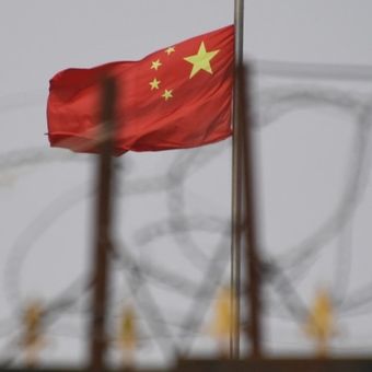 Bendera China berkibar di belakang kawat berduri di kompleks perumahan di wilayah Xinjiang barat China, 4 Juni 2019.