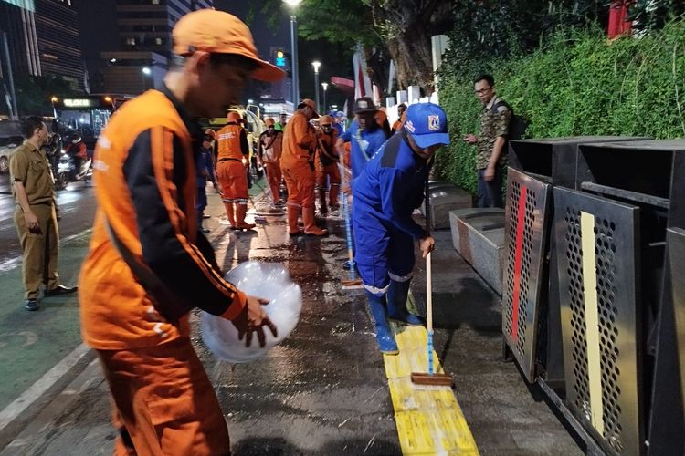 Petguas menuangkan cairan sabun saat membersihkan trotoar di Jalan MH Thamrin, Menteng, Jakarta Pusat, Selasa (22/8/2023). (KOMPAS.com/XENA OLIVIA)