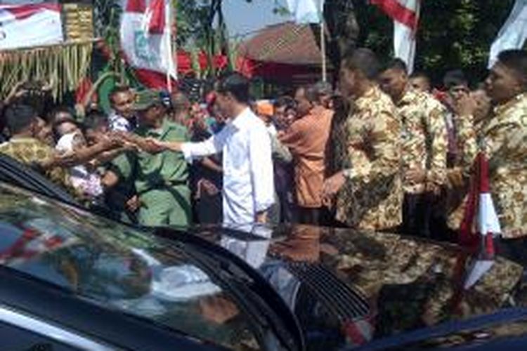 Presiden Jokowi saat bersalaman dengan warga Kabupaten Malang, Jawa Timur sembari membagi-bagikan buku dan kaos kepada warga di pinggir jalan. Kamis (21/5/2015).