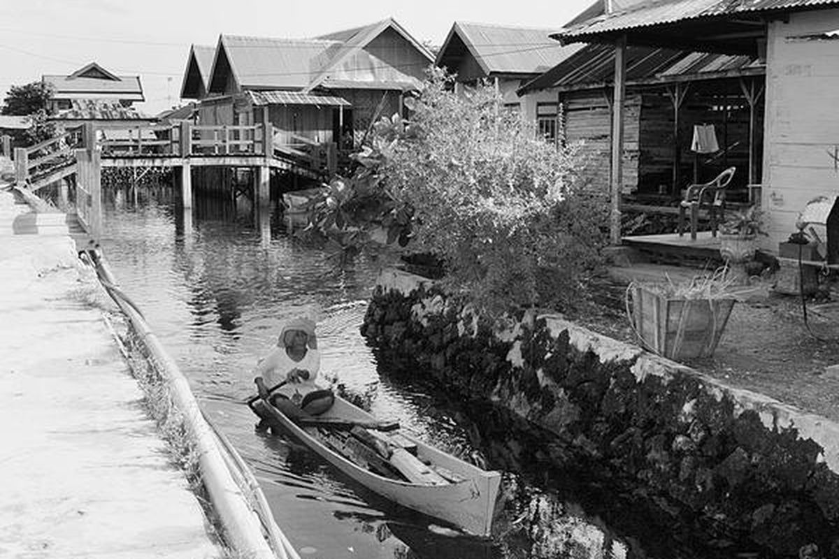 Warga DesaMola Selatan, Kecamatan Wangi-Wangi Selatan, Kabupaten Wakatobi, Sulawesi Tenggara, melintasi sungai di desa itu dengan sampan, Sabtu (19/6).