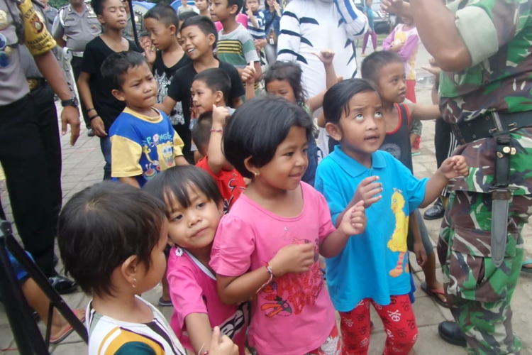 Anggota Polri dan TNI mengajak anak-anak di pengungsian berjoget dan bernyanyi mengikuti lagu.