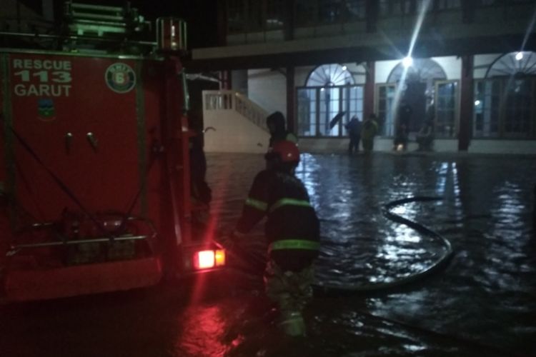 Sejumlah petugas pemadam kebakaran mengoperasikan mesin pompa di mobil pemadam untuk menyedot air yang menggenangi lingkungan Pesantren Persis 99 Rancabango Garut, Jawa Barat, Sabtu (7/4/2018) malam