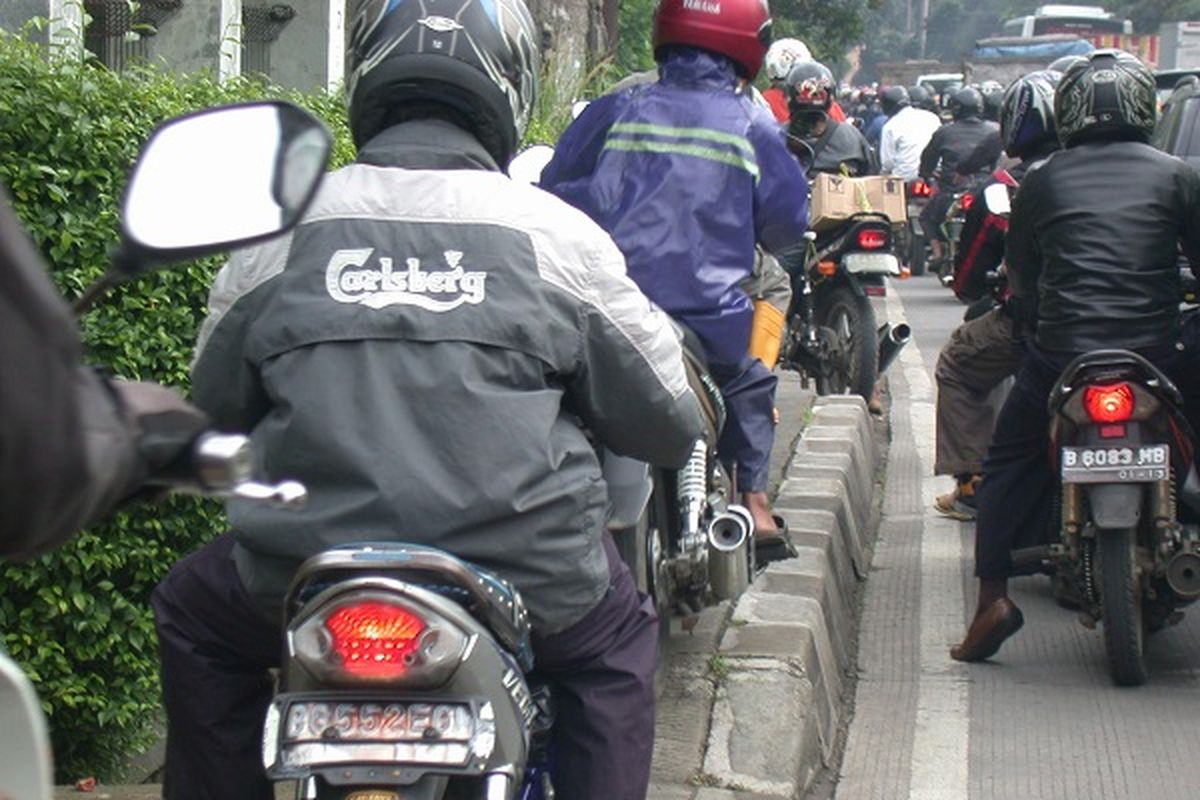 Pengendara motor melewati trotar untuk menghindari macet.