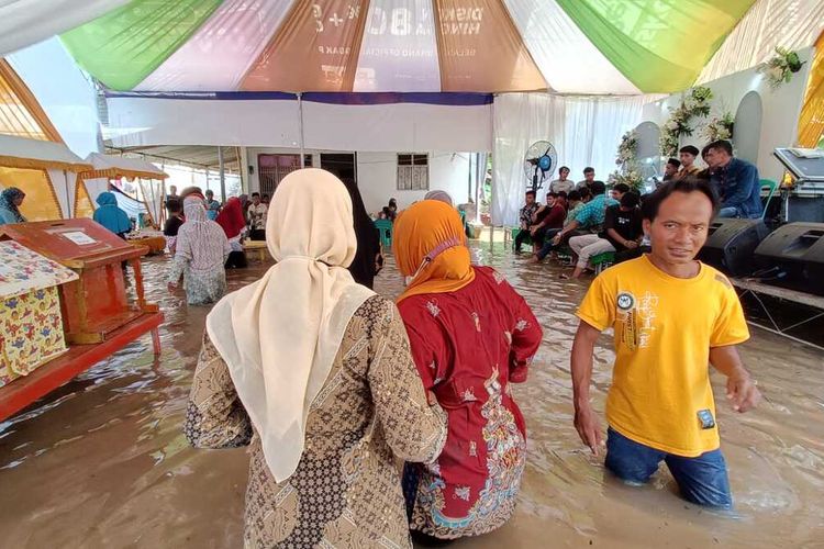Suasana pesta pernikahan di tengah banjir di Desa Nusawangkal, Kecamatan Nusawungu, Kabupaten Cilacap, Jawa Tengah, Rabu (16/3/2022).