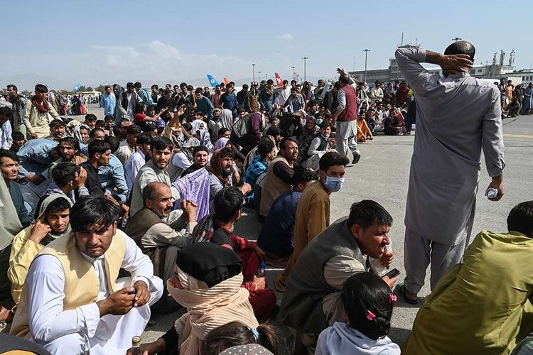 Orang-orang menunggu untuk dapat diberangkatkan dengan pesawat saat mereka berebut untuk melarikan diri ke luar negeri, di Bandara Kabul, Afghanistan, Senin (16/8/2021). Bandara Kabul dilanda kekacauan ketika ribuan orang mencoba melarikan diri dari Taliban yang dilaporkan segera menguasai penuh Afghanistan.