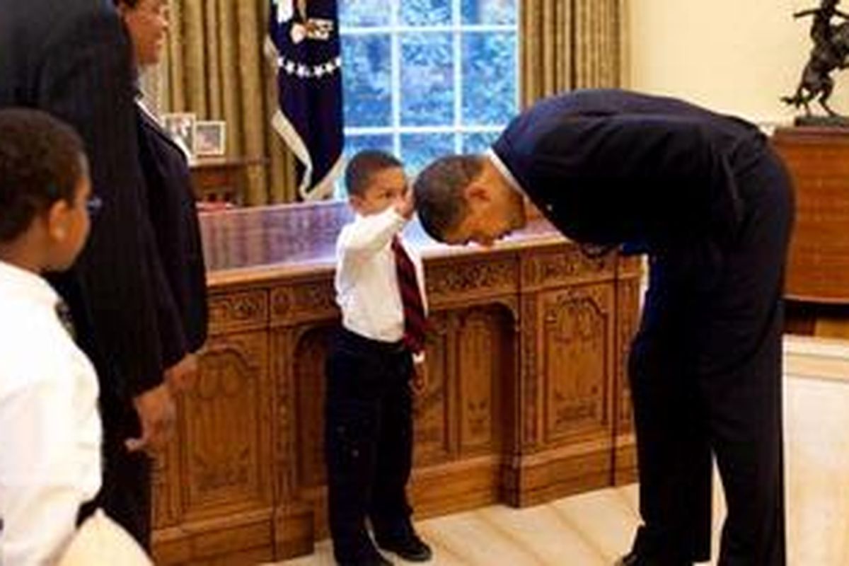 Presiden Barack Obama membungkuk ketika Jacob Philadelphia, anak seorang anggota staf Gedung Putih menyentuh rambutnya saat berkunjung ke Ruang Oval, 8 Mei 2009.