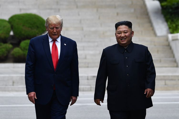 Pemimpin Korea Utara (Kim Jong Un) tersenyum sambil berjalan bersama Presiden Amerika Serikat Donald Trump di Garis Demarkasi Militer yang memisahkan Korut dan Korea Selatan (Korsel) pada Minggu (30/6/2019).