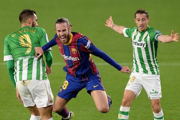 Barcelona's Spanish defender Oscar Mingueza (C) challenges Real Betis' Spanish forward Borja Iglesias (L) and Real Betis' Mexican midfielder Andres Guardado during the Spanish league football match between Real Betis and FC Barcelona at the Benito Villamarin stadium in Seville on February 7, 2021. 