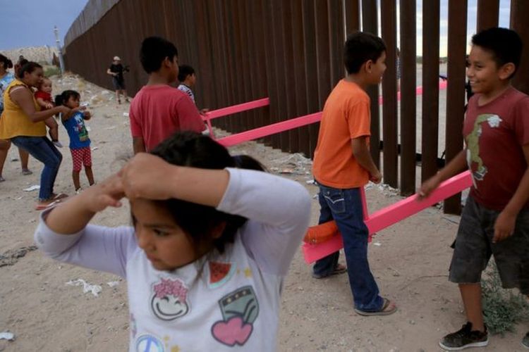 Anak-anak bermain jungkat-jungkit pink di tembok perbatasan AS-Meksiko.