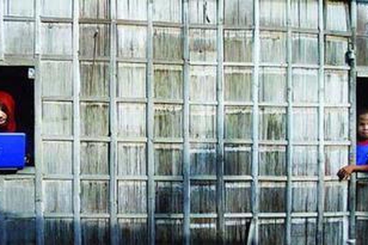 Erwin Puspaningtyas Irjayanti (kiri) sedang bekerja dengan laptopnya di sebuah rumah sederhana di Passau, Sendana, Majene, Sulawesi Barat, Rabu (19/1/2011). Para peserta di Majene, umumnya ditempatkan di daerah sangat terpencil yang belum memiliki saluran listrik PLN.