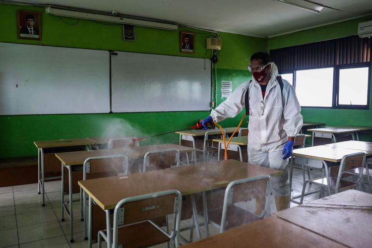 An Indonesian Red Cross staff sprays disinfectant in a classroom of one of the public schools in Central Jakarta.