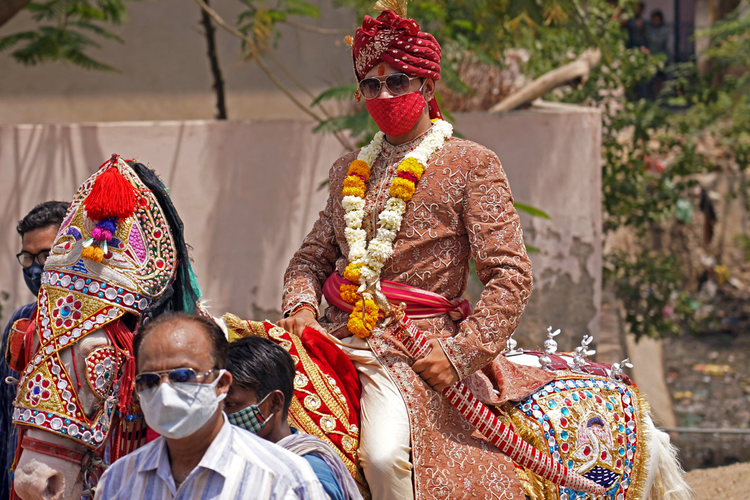 Ilustrasi pengantin pria India berpakaian tradisional mengenakan masker sebagai tindakan pencegahan terhadap virus corona Covid-19 duduk di atas kuda saat ia mengambil bagian dalam prosesi pernikahan India.