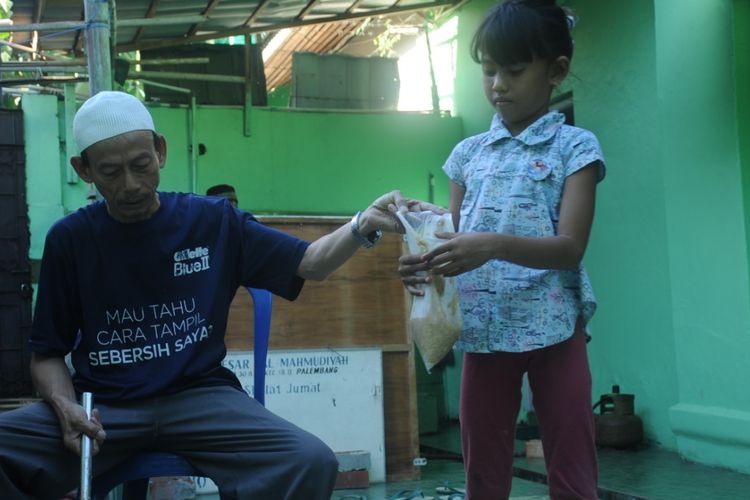 Kartibi membagikan bubur syuro kepada anak-anak. Pembagian bubur syuro secara gratis ini berlangsung selama bulan ramadhan.