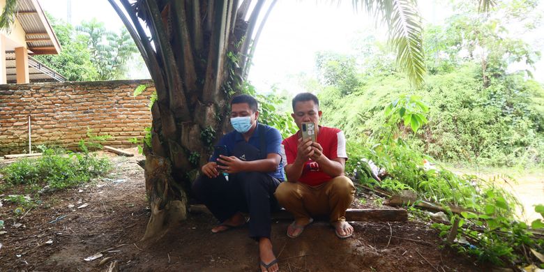Warga Dusun Baru Kecamatan Pelepat mencari sinyal di bawah pohon sawit. Lokasi ini selalu ramai pada jam-jam tertentu karena warga ingin menelpon atau sekadar melihat sosial media.