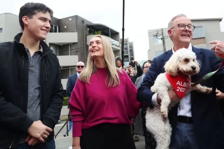 Pemimpin buruh Anthony Albanese memegang anjing Toto saat berkampanye di samping putra dan pasangannya di Sydney.