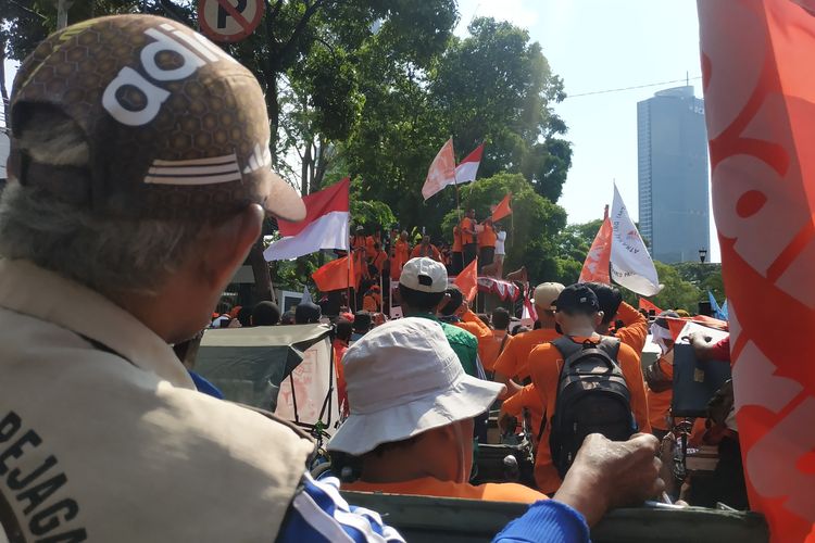 Tukang becak yang hadir dalam Karnaval Klas Pekerja dari Partai Buruh sedang menyaksikan orasi Presiden Partai Buruh Said Iqbal di atas mobil komando di depan kantor KPU RI, Jumat (12/8/2022).