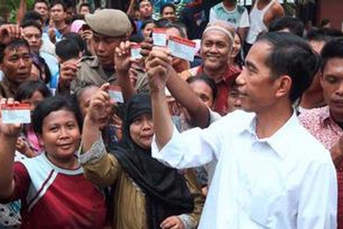 Bersama perwakilan warga penerima Kartu Jakarta Sehat,  Gubernur DKI Jakarta, Joko Widodo, menunjukkan kartu usai perkenalan program itu di Kelurahan Pademangan Timur, Jakarta Utara, Sabtu (10/11/2012). Kartu jaminan pengobatan gratis bagi warga di Puskesmas atau Kelas 3 di 88 rumah sakit yang bekerja sama dengan pemerintah provinsi.  