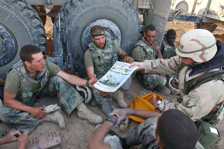 Dalam foto yang dirilis Angkatan Laut Amerika Serikat (AS) pada 7 April 2003, Komandan Sersan Mayor John Sparks membagikan koran militer Stars and Stripes kepada Marinir dari Peleton Senjata Kompi India 3-2. Marinir tersebut merupakan bagian dari Gugus Tugas Tarawa, yang dikerahkan untuk menopang Operation Iraqi Freedom.