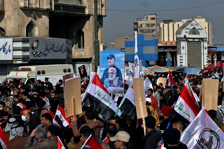 Pendukung Pasukan Mobilisasi Rakyat (PMF) memegang poster Abu Mahdi al-Muhandis dan Jenderal Qassem Soleimani di Tahrir Square, Irak, Minggu (3/1/2021). Ribuan rakyat Irak berkumpul di tempat itu untuk memperingati 1 tahun pembunuhan Soleimanil dan al-Muhandis dalam serangan pesawat tak berawak AS.