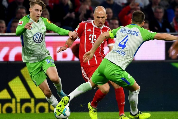 Pemain Bayern Muenchen, Arjen Robben, mencoba melewati hadangan dua pemain Wolfsburg pada pertandingan Bundesliga di Allianz Arena, Jumat (22/9/2017) malam. 