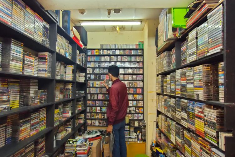 Salah satu pengunjung sedsng melihat-lihat kaset lawas di kios milik Ujang di Lantai bawah Blok M Square, Jakarta Selatan, Kamis (18/11/2021).