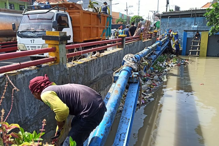 Petugas BMSDA Sidoarjo membersihkan tumpukan sampah di bawah jembatan Kutuk