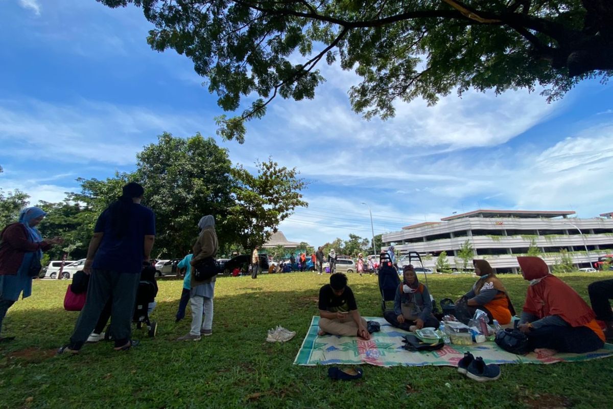 Pengunjung yang membawa bekal dan menggelar tikar di area TMII, Minggu (20/11/2022). 