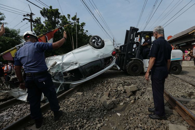 Petugas melakukan evakuasi mobil Mobilio dengan nomor polisi B 1563 NYZ yang tertabrak KRL Commuter Line di Depok, Jawa Barat, Rabu (20/4/2022). Akibat kejadian ini jadwal KRL dari Depok menuju Jakarta terganggu.