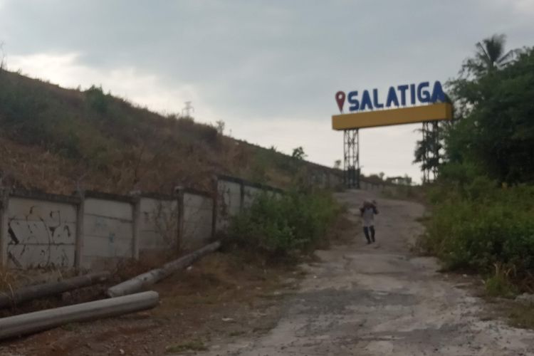 Seorang pencari rumput berjalan di lokasi yang dipersiapkan menjadi exit tol baru di Salatiga.