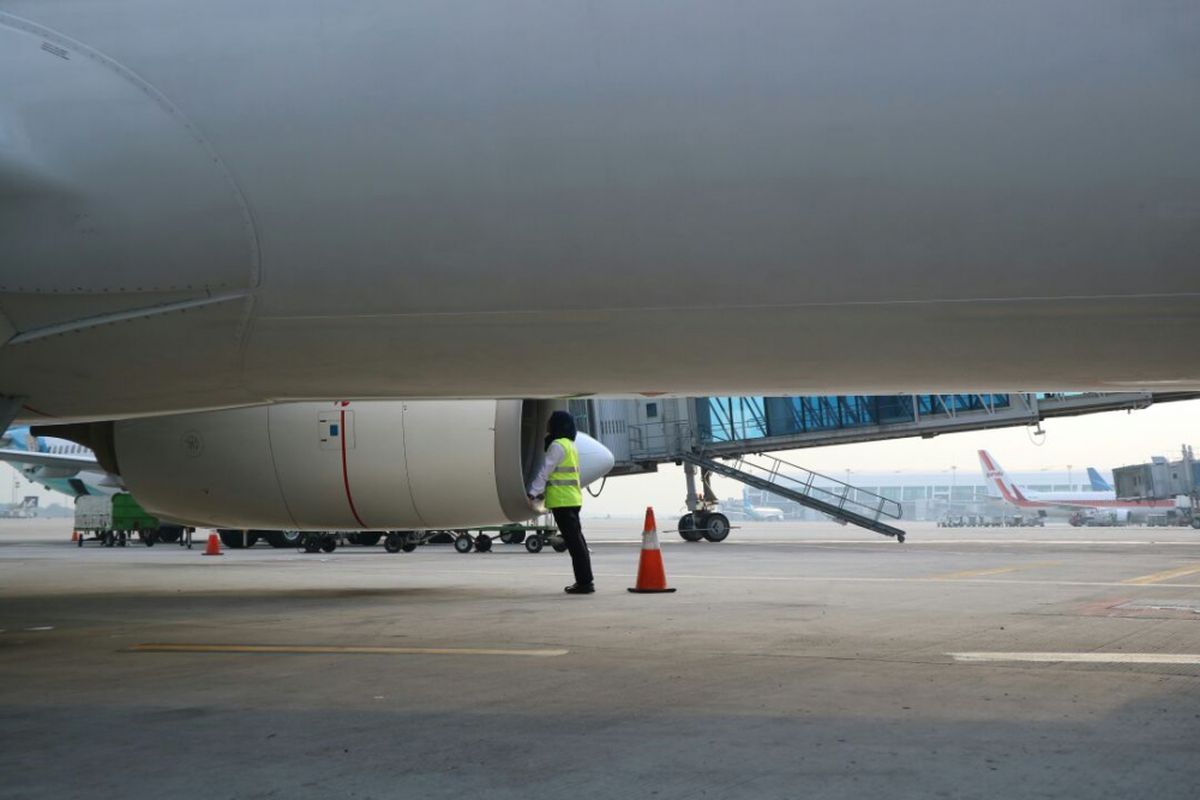 Staf teknisi perempuan Garuda Indonesia memeriksa bagian pesawat