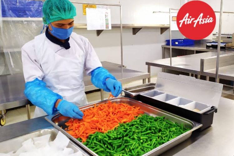 Staf produksi inflight meals AirAsia menggunakan APD dalam menyiapkan pesananan makanan untuk penumpang.