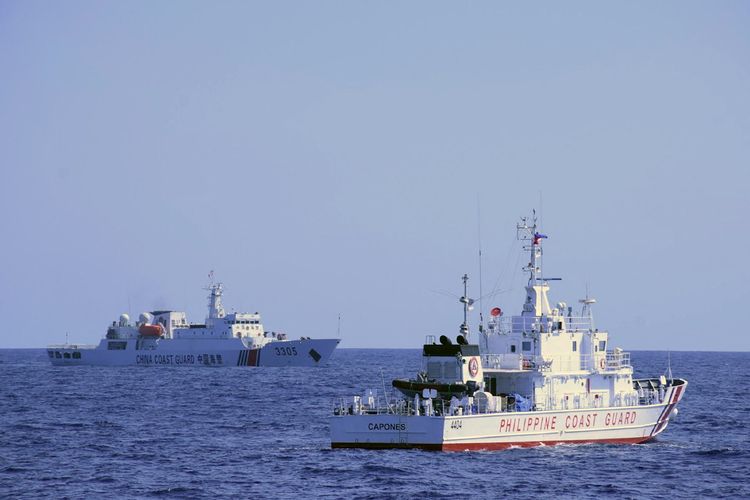 Kapal penjaga pantai China (kiri) mengikuti kapal penjaga pantai Filipina (kanan) saat latihan patroli maritim di Beting Scarborough, Laut China Selatan, 2 Maret 2022.