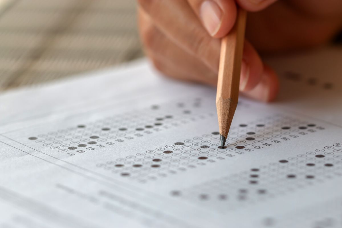 Student hand testing doing test exam with pencil drawing selected choices on answer sheet in school final exams at college or university. Taking multiple choice for assessment in examination classroom