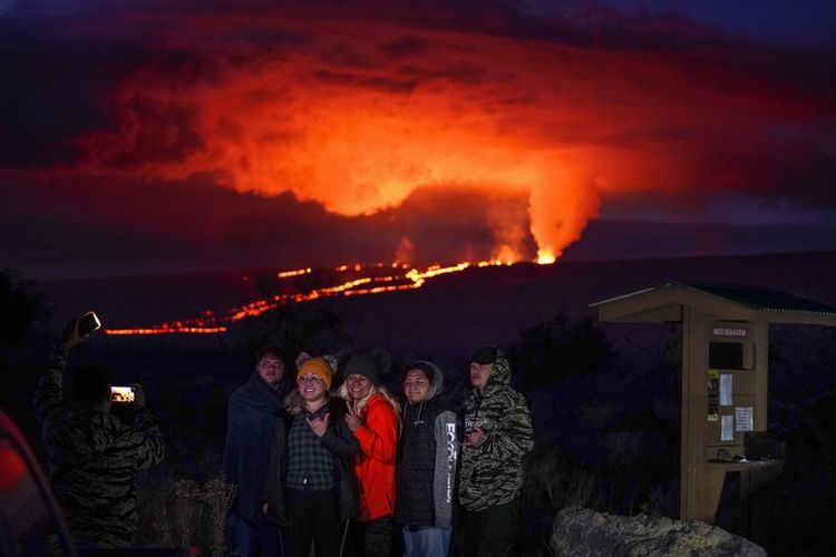 Pengunjung berpose di depan letusan Mauna Loa Hawaii, Rabu (30/11/2022).