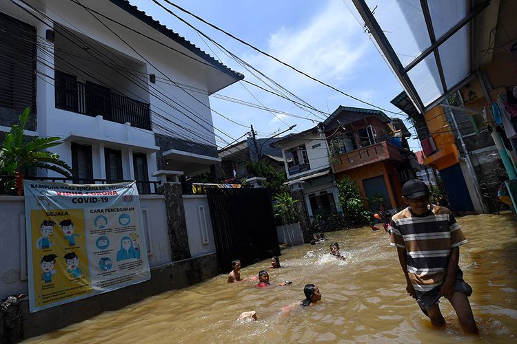 Sejumlah anak bermain air saat banjir melanda kawasan permukiman di Petogogan, Kebayoran Baru, Jakarta Selatan, Senin (5/10/2020). Banjir tersebut terjadi akibat meluapnya Kali Krukut.